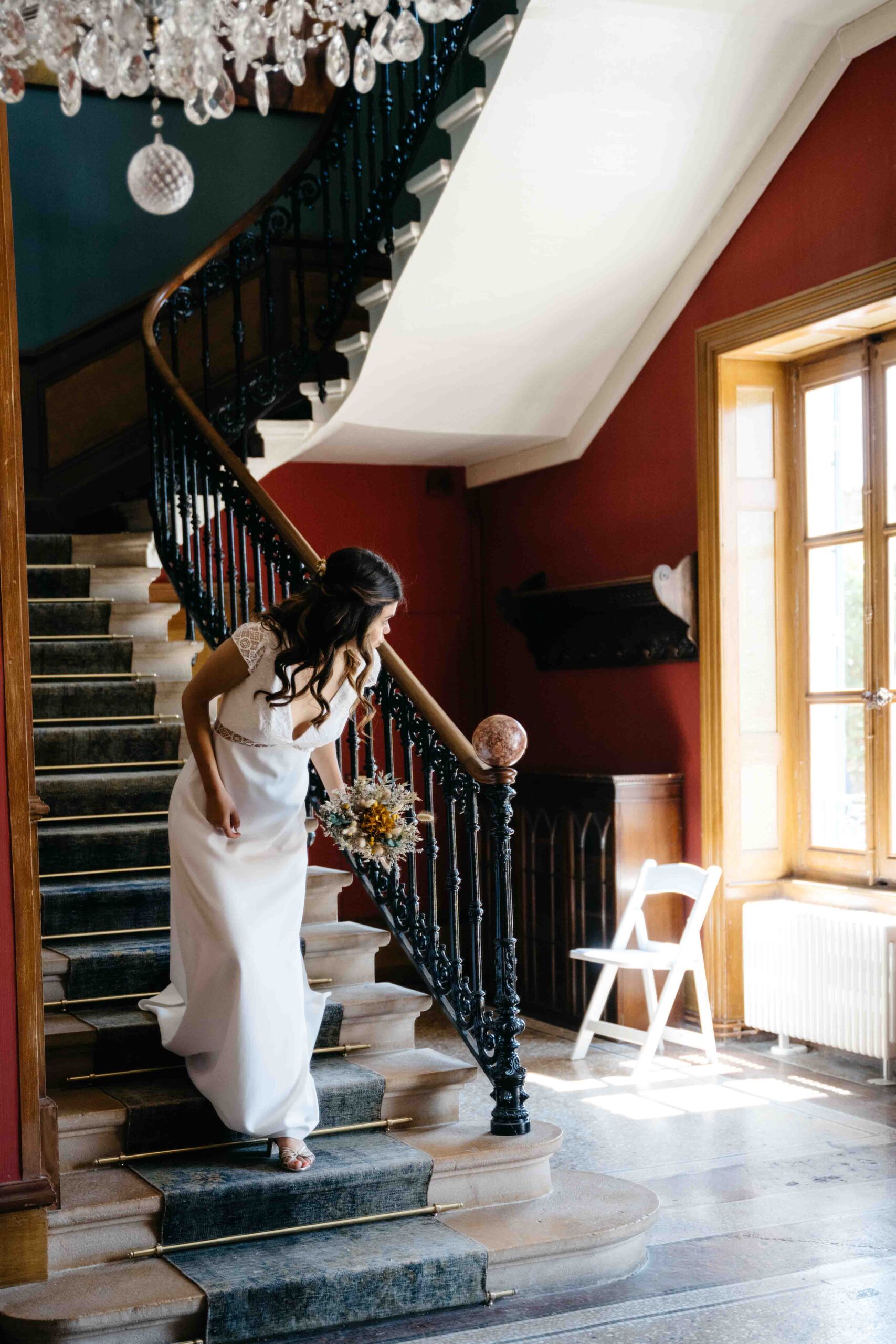 la mariée descend les escaliers avant la cérémonie et se penche en avant essayant de regarder dehors
