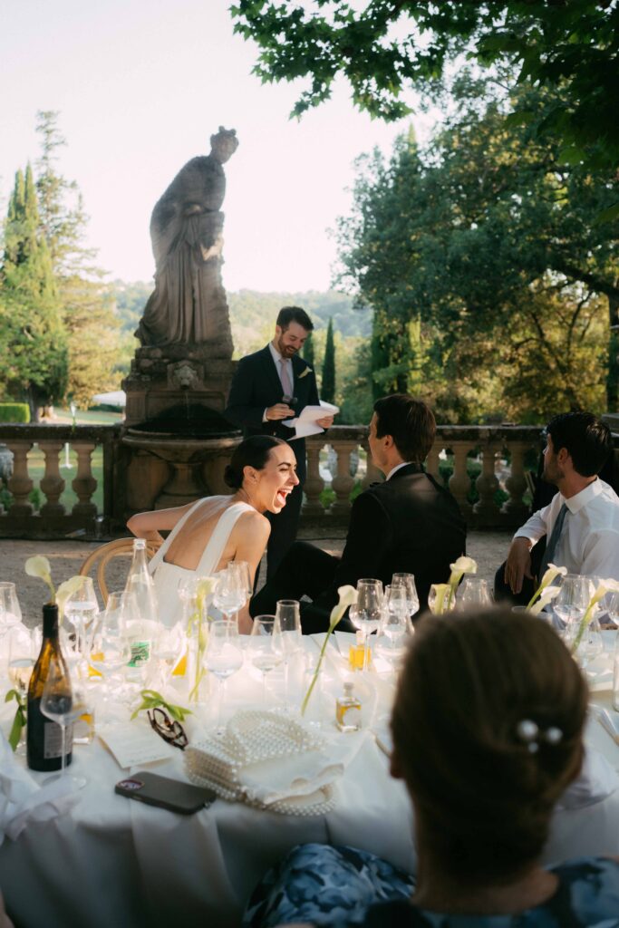 bride laughing at the speech of her brother during dinner outside